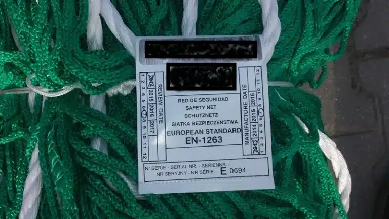 Etykieta siatki ochronnej z oznaczeniem EN 1263, numerem seryjnym oraz datą produkcji i przeglądu