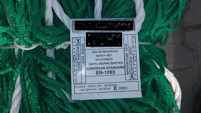 Etykieta siatki ochronnej z oznaczeniem EN 1263, numerem seryjnym oraz datą produkcji i przeglądu